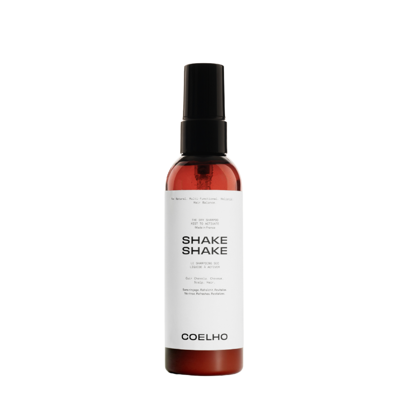 A bottle of Coelho Shake Shake spray with a black spray nozzle and a white label, set against a plain white background.