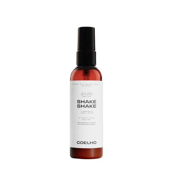 A bottle of Coelho Shake Shake spray with a black spray nozzle and a white label, set against a plain white background.